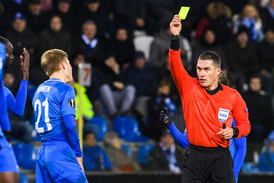 Jere Uronen of Genk receives a yellow card from referee