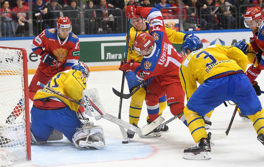 Sweden's goalie Lars Johansson, left, struggles for a puck