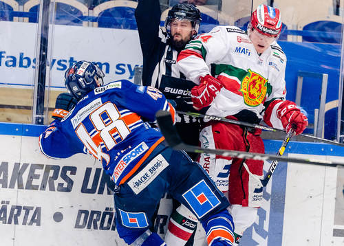 Linjedomare Anders Jansson hamnar i en tackling mellan