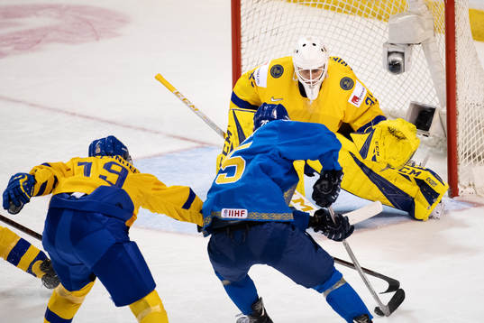 Dmitri Mitenkovk of Kazakhstan attacks against goaltender