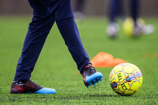Fotbollsskor, och en fotboll på konstgräs