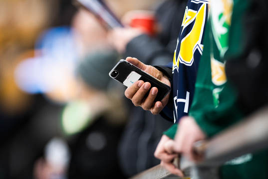 En HV71-supporter tittar i mobilen