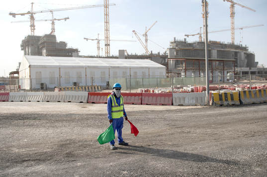 A worker is seen outside the construction of the Lusail