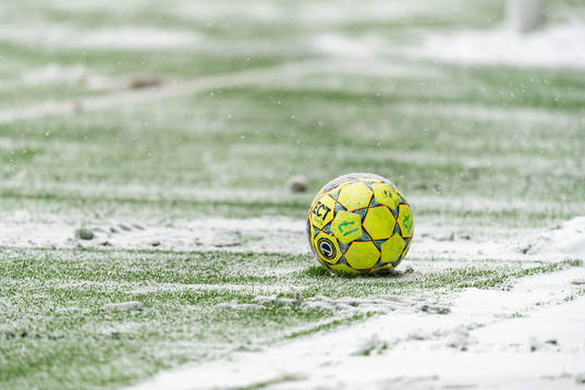 En fotboll i snö på konstgräset