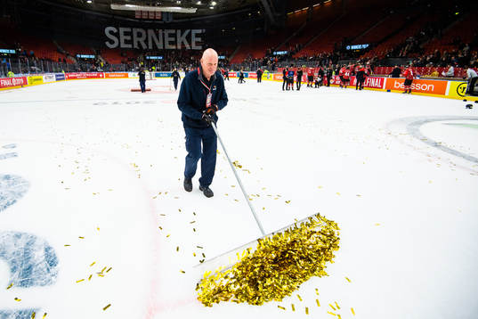 A janitor scrapes gold glitter of the ice