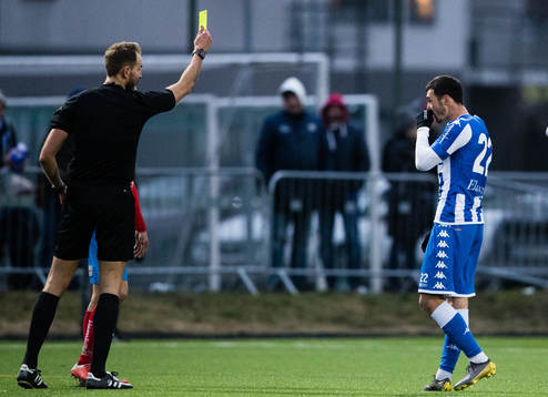 Domare Andreas Johansson delar ut ett gult kort till IFK
