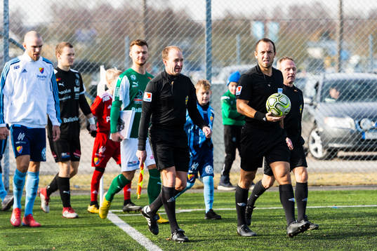 Båda lagens spelare gör entré till fotbollsmatchen i