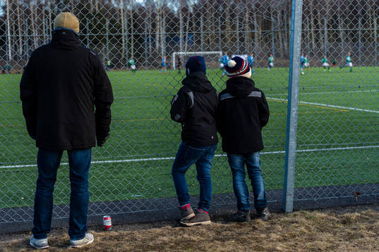 Pappa med två söner ser matchen bakom staketet