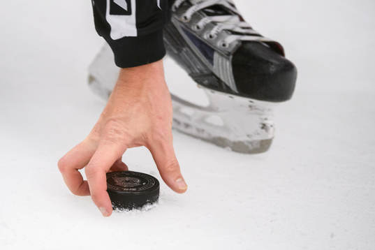 Domaren plockar upp en puck