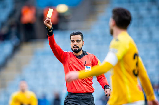 Domaren Mohammed Al-Hakim höjer det gula kortet