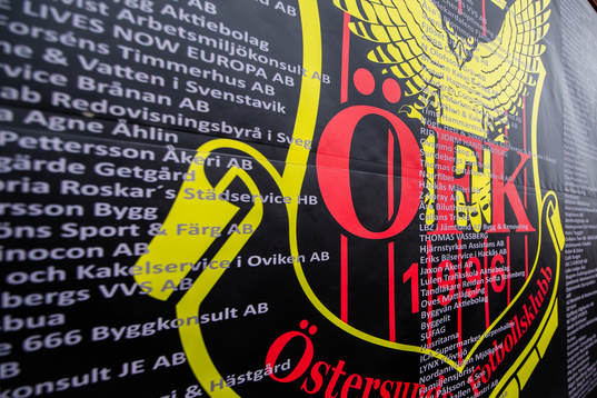 Östersunds klubbmärke på en skylt med sponsorer