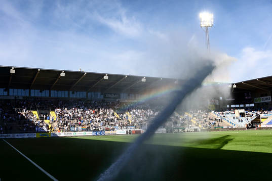 Vattning av konstgräset ger regnbågen framför Curva