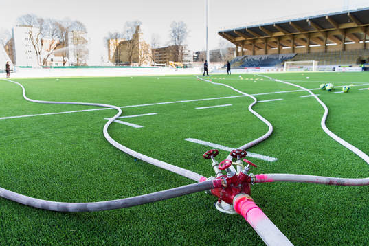 Planen vattnas för hand innan fotbollsmatchen i