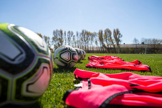 Fotbollar och träningsvästar ligger uppradade