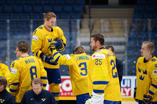 Adrian Kempe helps Oskar Lindblom of Sweden at a photo shoot