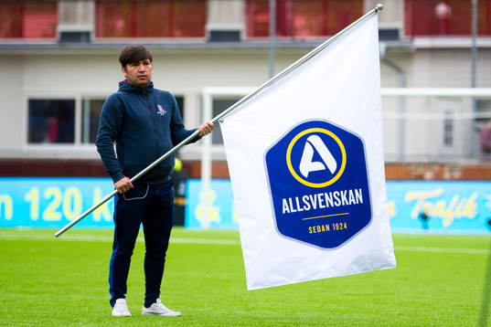 En funktionär med en flagga med Allsvenskans logotyp