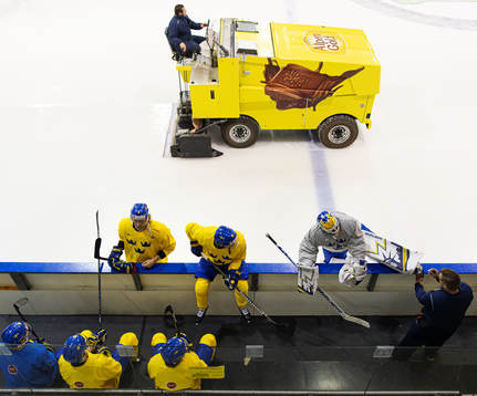 A Zamboni ice resurfacer passes by players of Sweden at a