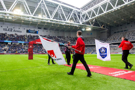 Funktionärer med flaggor med Svenska Spels och
