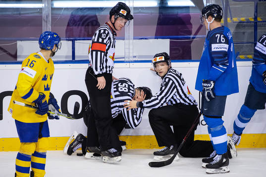 One of the referees is hit by a puck