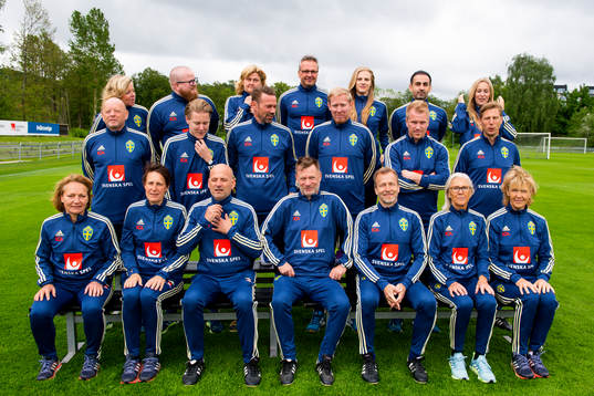 Staff prepare for a team photo shoot with coaching staff of