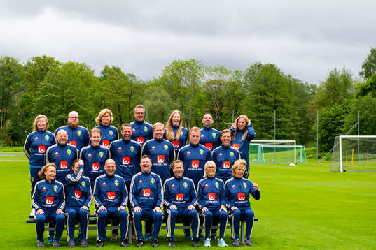 Staff prepare for a team photo shoot with coaching staff of