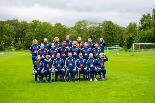 Staff prepare for a team photo shoot with coaching staff of