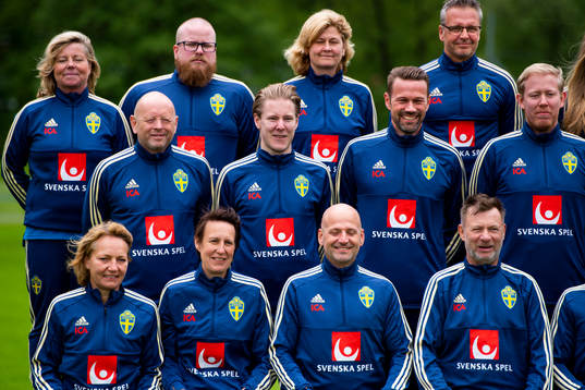 Staff prepare for a team photo shoot with coaching staff of