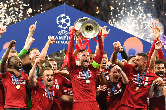 Jordan Henderson of Liverpool raises the throphy in front