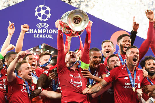 Jordan Henderson of Liverpool raises the throphy in front