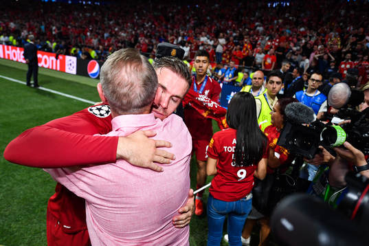 Jordan Henderson of Liverpool hugs a man as he celebrate