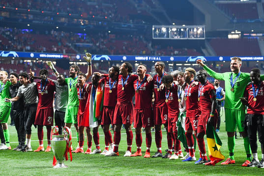 Players of Liverpool celebrate in front of the trophy