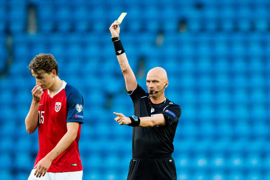 Sander Berge of Norway is shown a yellow card by Sergei
