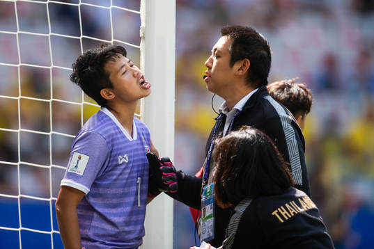 Goalkeeper Waraporn Boonsing of Thailand is attended to