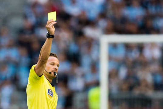 Domare Kristoffer Karlsson delar ut ett gult kort