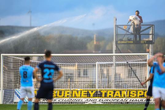 A camera man protects his camera when a sprinkler starts