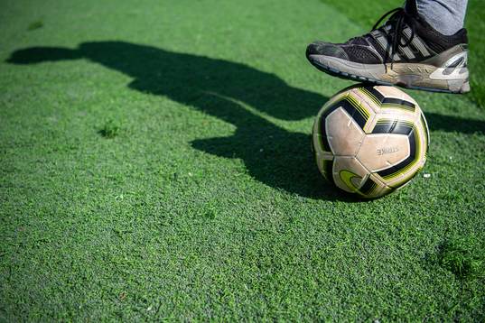 En person med en fotboll på konstgräs och gummigranulat