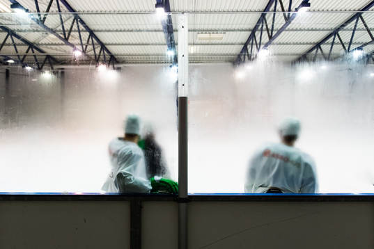 Spelare syns genom imma på sargens plexiglas på en