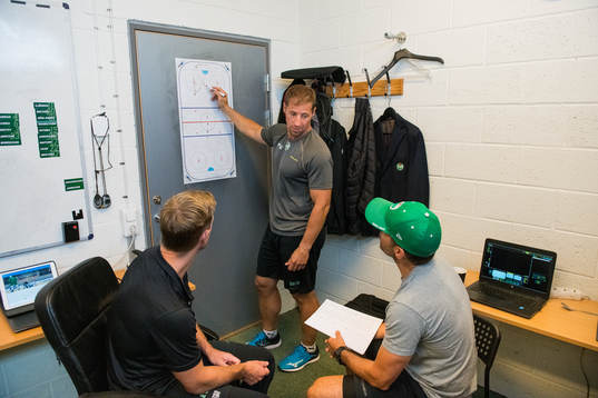 Rögles tränare Cam Abbott ritar på en whiteboard i