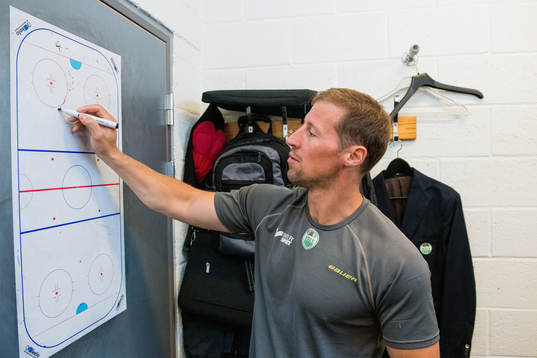 Tränare Cam Abbott ritar på en whiteboard i tränarrummet