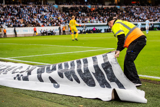 En funktionär tar hand om en reklamskylt som kommit in på