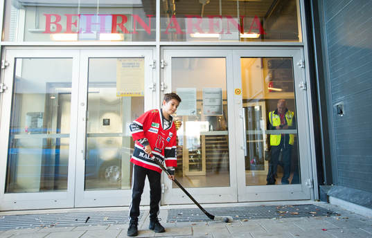 Kille med Örebrotröja och hockeyklubba utanför entrén