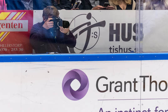 Fotograf fotar genom håll i plexiglaset