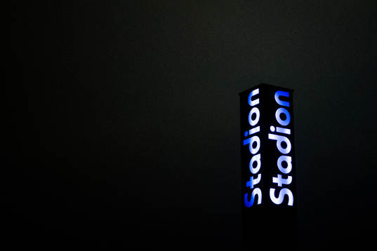 A sign lights up the dark sky with the logo for Stadion,