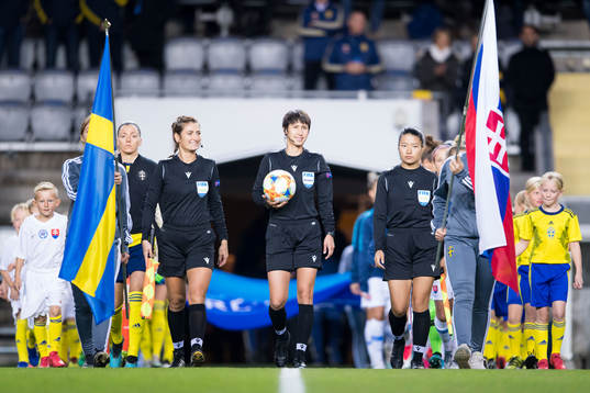 Referee Elvira Nurmustafina walks into the pitch together