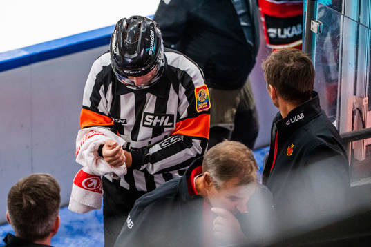 Domare Sören Persson tar sig för armen och lämnar isen