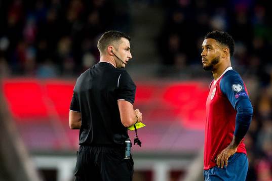 Referee Michael Oliver gives a yellow card to Joshua King