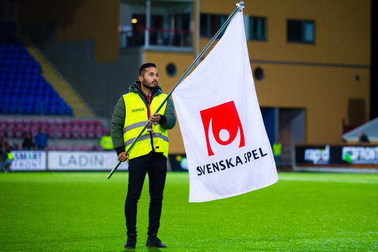 En fanbärare med en flagga med Svenska Spels logotyp