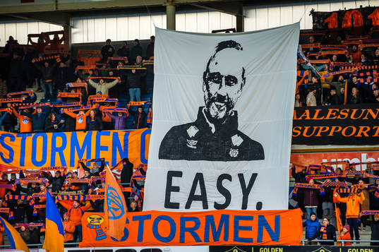 Spectators in the stands with a tifo of Lars Bohinen, head