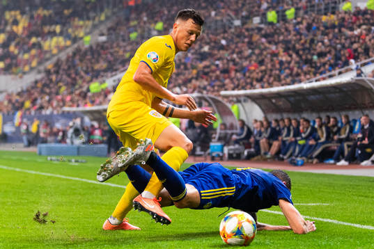 Adrian Rus of Romania tackles Marcus Berg of Sweden