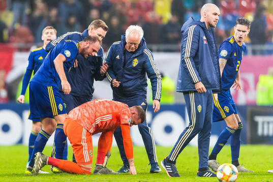Medical staff attend to goalkeeper Robin Olsen of Sweden